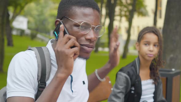 Close-up of African American Man Talking on the Phone As Bored Little Girl Trying To Draw His