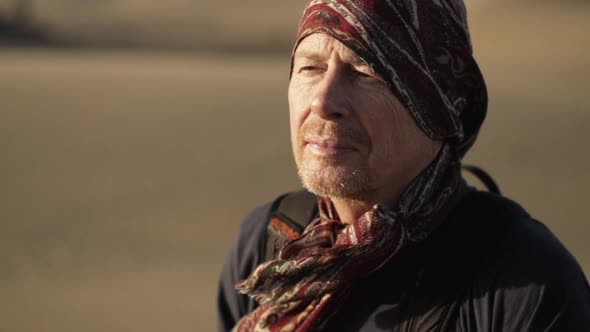 Man In Headscarf Walking Through Desert