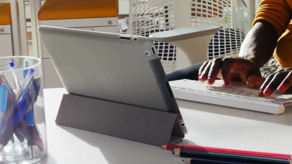 Mid section of female executive typing on keyboard at desk