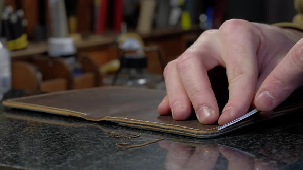 Handicraftsman Cutting Edges of New Leather Wallet