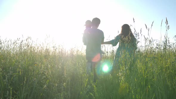 Korean Family with Their Daughter Lie in a Field in the Grass at Sunset