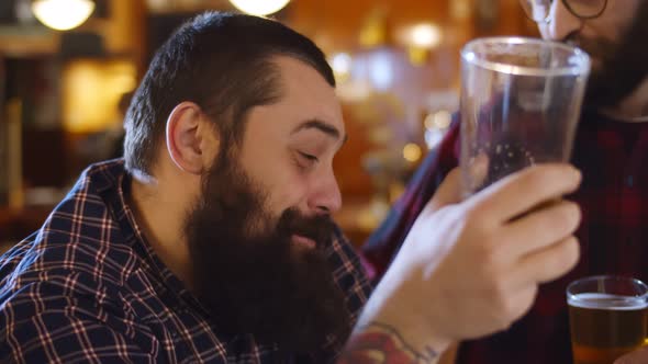 Close Up of Bearded Man Drinking Beer and Talking To Friends in Pub