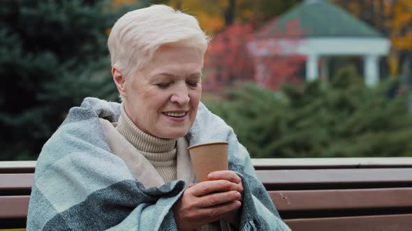 Happy Mature Single Middle Aged Woman Covered with Warm Plaid Drinking Hot Coffee Disposable Cup