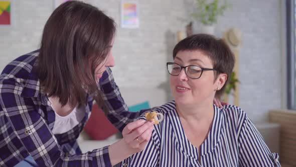 Young Woman Helps Put a Hearing Aid on the Ear of a Hard of Hearing Woman