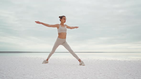 Parallax Full Length Shooting Young Beautiful Fitness Woman Practicing Yoga Postures on Dry Salt