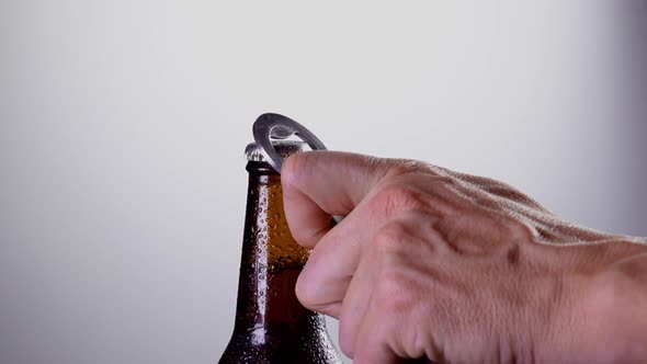 Closeup of a hand opening a bottle of beer in slow motion