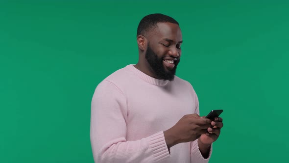 Young Afro American Man in Casual Chatting on Smartphone and Smiling on Green Screen Chroma Key