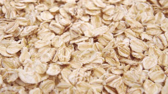 Oat flakes. Uncooked oatmeal. Rolled whole grains. Macro. Slow rotation