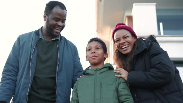 Laughing African family standing near the house