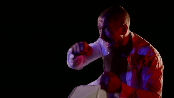 a Man in an Unbuttoned White Shirt is Boxing on a Dark Background