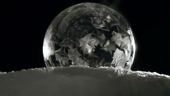 Ice Bubble with Icy Crystals Freezing Fast in Cold Winter in Black Background