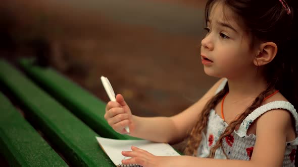 Little Girl Draws On Paper. Baby Girl Small Kid Enjoying Creative Art. Child Painting With Pencil.