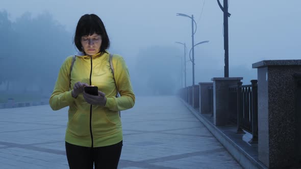 Scared Lost Short Hair Woman with a Smartphone in the Fog