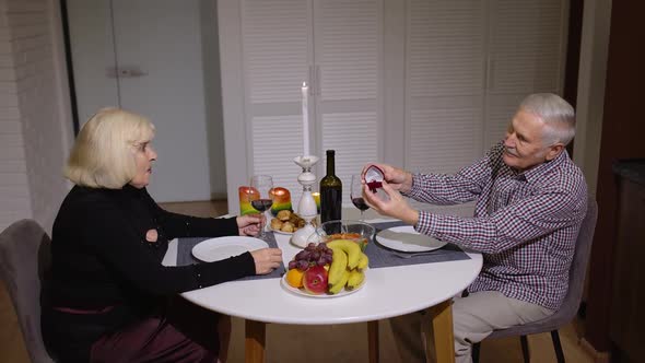 Senior Woman Being Surprised By Marriage Proposal with Engagement Ring of Her Grandfather Husband