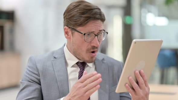 Portrait of Businessman Reacting To Loss on Tablet