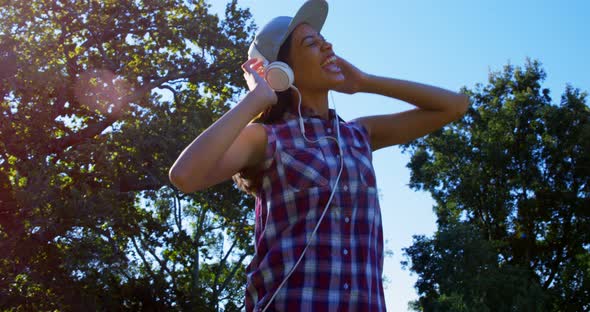 Woman dancing while listening music in park 