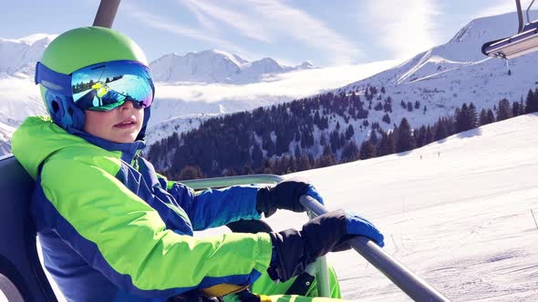 Boy Sit in Sport Outfit with Helmet Mask on Chairlift