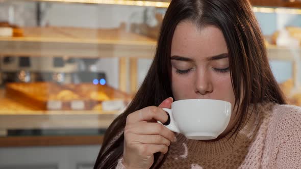 Lovely Young Woman Smiling To the Camera, Drinking Coffee in the Morning