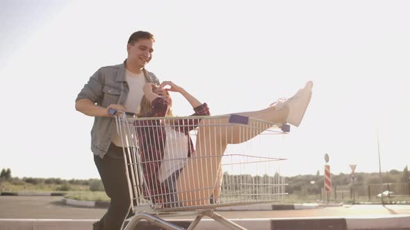 A Man Runs and Pushes a Supermarket Cart Rolling a Girl in It Crazy Fun of Students