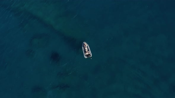 Overhead Top Down Birds View of 3 Young Adults in Boat on Crystal Clear Blue Water