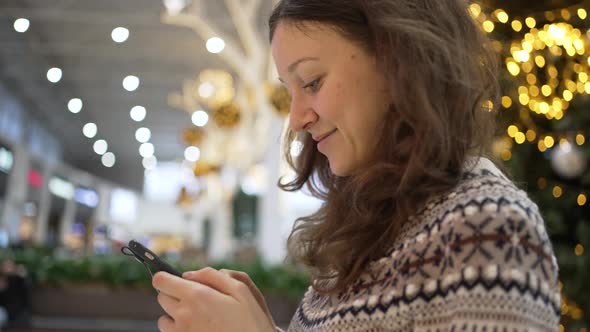 Young Brunette Woman Checks Social Media in Shopping Mall