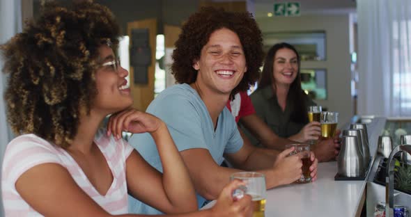 Diverse group of happy friends drinking beers and smiling at a bar