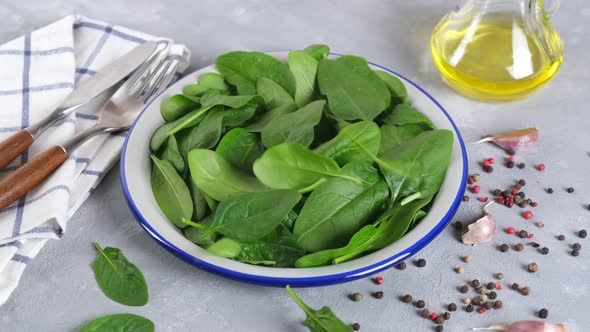 Fresh spinach. The leaves fall into a plate. Healthy food concept,