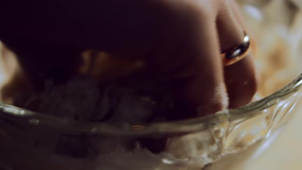 Macro of Female Hand Mixing Food Ingredients in Glass Bowl