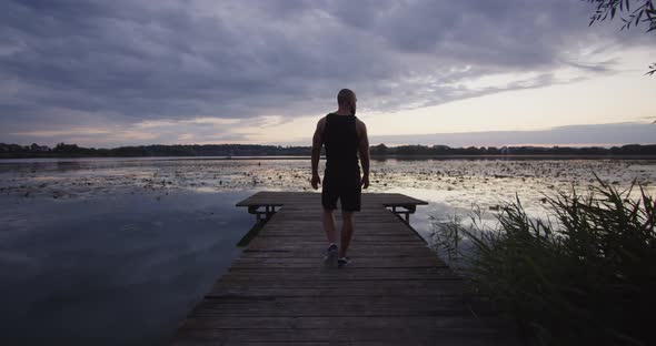 A Young Guy Walks on the River Bank at Sunset