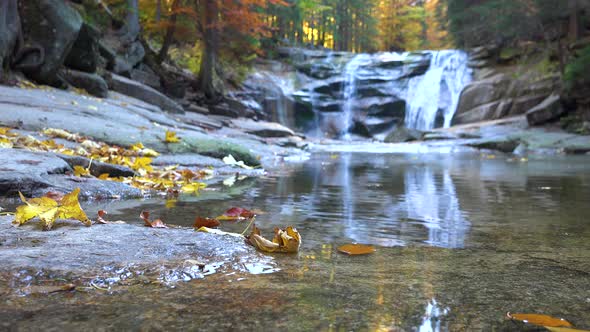 Closeup on Rippling Water in a Forest - a Low Waterfall in the Blurry Background