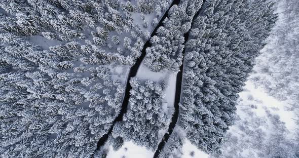 Overhead Aerial Top View Over Hairpin Bend Turn Road in Mountain Snow Covered Winter Forest