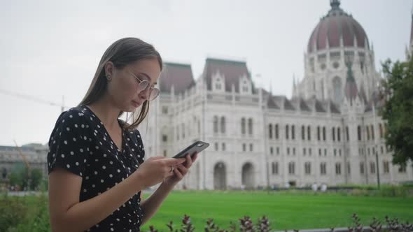 Young Woman is Reading Message in Smartphone Outdoors