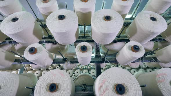 White Threads on Coils Spinning on a Factory Machine