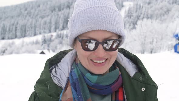 Someone Hit a Young Cheerful Woman with a Snowball in the Glasses During a Snowball Fight