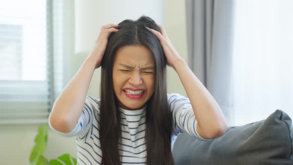 Portrait of Asian young angry woman sit alone on sofa in living room.