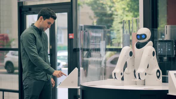 A Man is Ordering a Coffee and a Robot is Serving Him