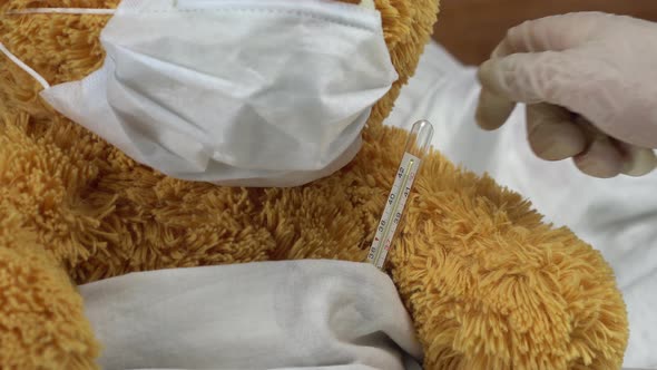 A Teddy Bear Measures the Temperature with a Mercury Thermometer. The Doctor Takes the Thermometer