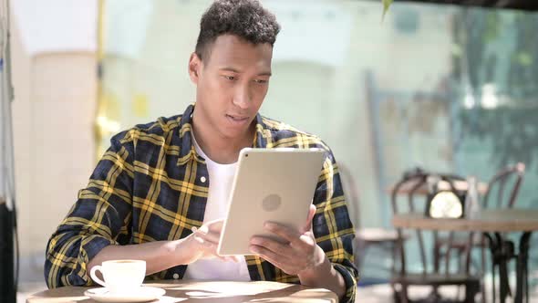 Winning Young African Man Excited for Success on Tablet, Outdoor Cafe