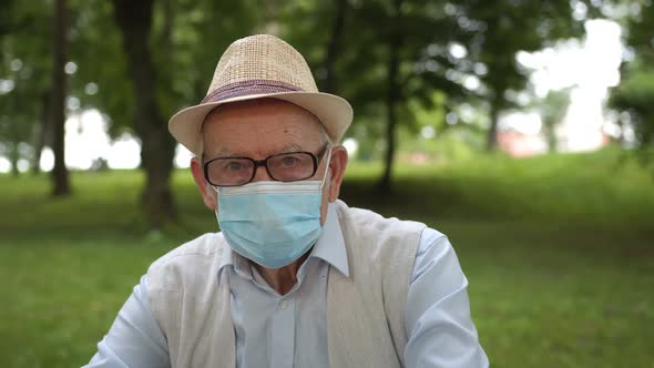 An Old Man Was Vaccinated and Sitting in a Medical Mask on a Bench