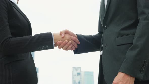 Close up of Asian young business man and woman partnership in formal suit make handshake in the city