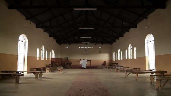 African Christian priest kneeling and praying in an empty church.