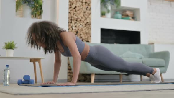 Young African Woman Doing Pushups on Yoga Mat at Home