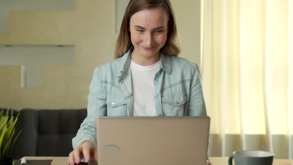 Beautiful Young Woman Working on Laptop Computer While Sitting at the Living Room