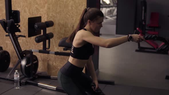 Strong Sportive Brunette Girl in Her 20's Performing Battle Ropes Workout at the Gym