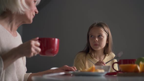 Happy grandmother and granddaughter eating breakfast