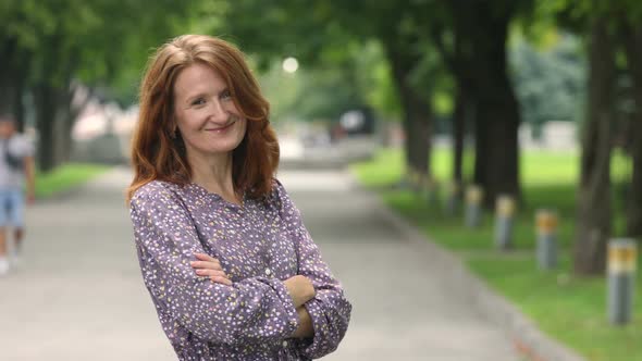 Portrait Of Young Smiling Woman Standing In The Urban Park Alley