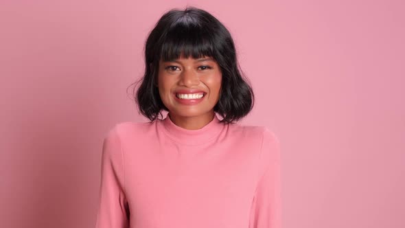 African Woman Dressed in Pink Golf Smiling Happily and Playfully Winking at the Camera