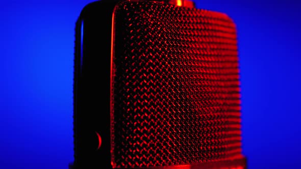 Condenser Microphone Rotates with Blue and Red Backlight. Professional Audio Recorder Close-up