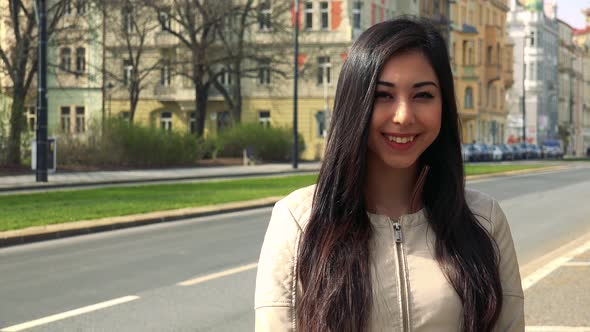 A Young Asian Woman Smiles at the Camera in a Street in an Urban Area