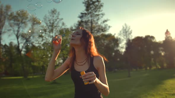Portrait of Beautiful Redhair Young Sexy Woman. Blow Bubble in the Park